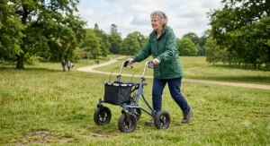 A woman navigating an uneven grassy park lawn with a lightweight all terrain rollator walker featuring shock-absorbing wheels.